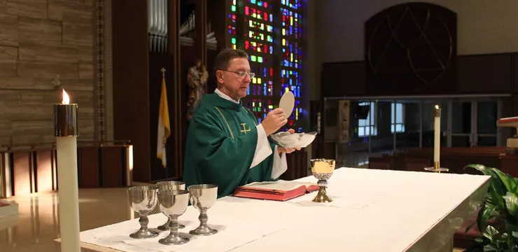 Ksiądz ubrany w zielone szaty liturgiczne udziela ślubu w Anglii