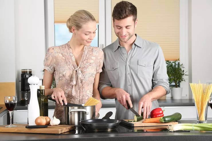 Uśmiechnięta kobieta i mężczyzna gotują wspólnie w stylowo urządzonej kuchni